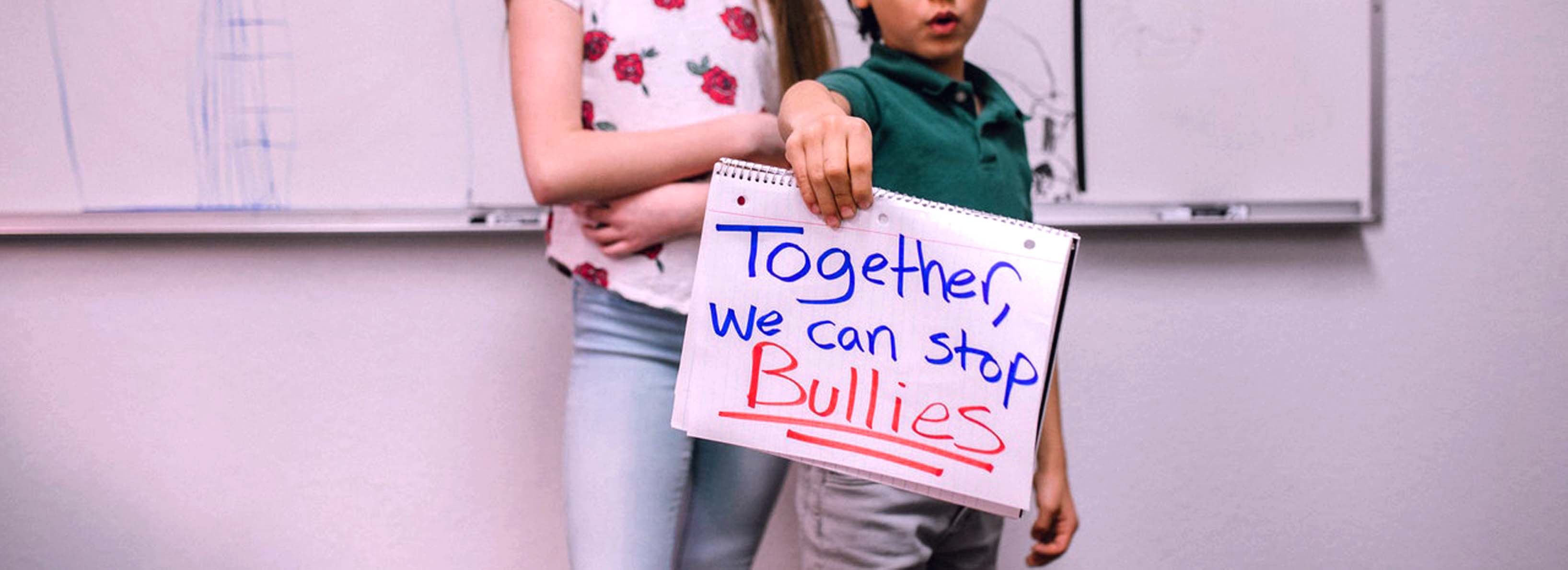 Boy holding a sign saying together we can stop bullies